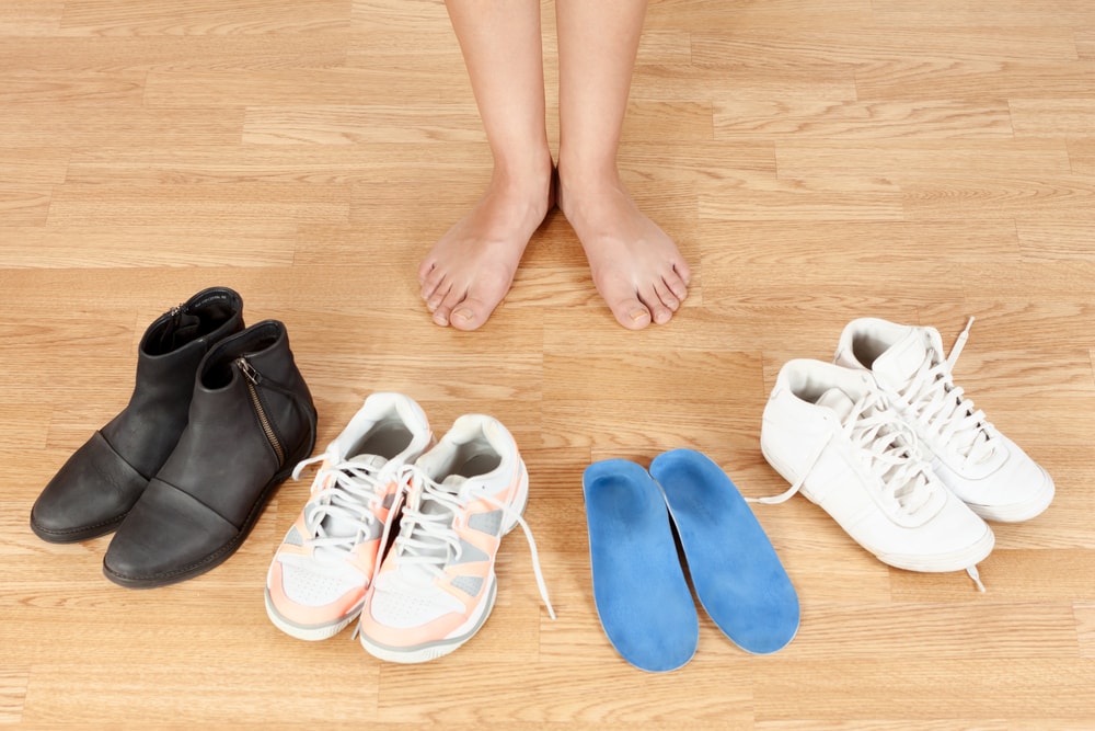 Feet with several pairs of shoes and orthotics